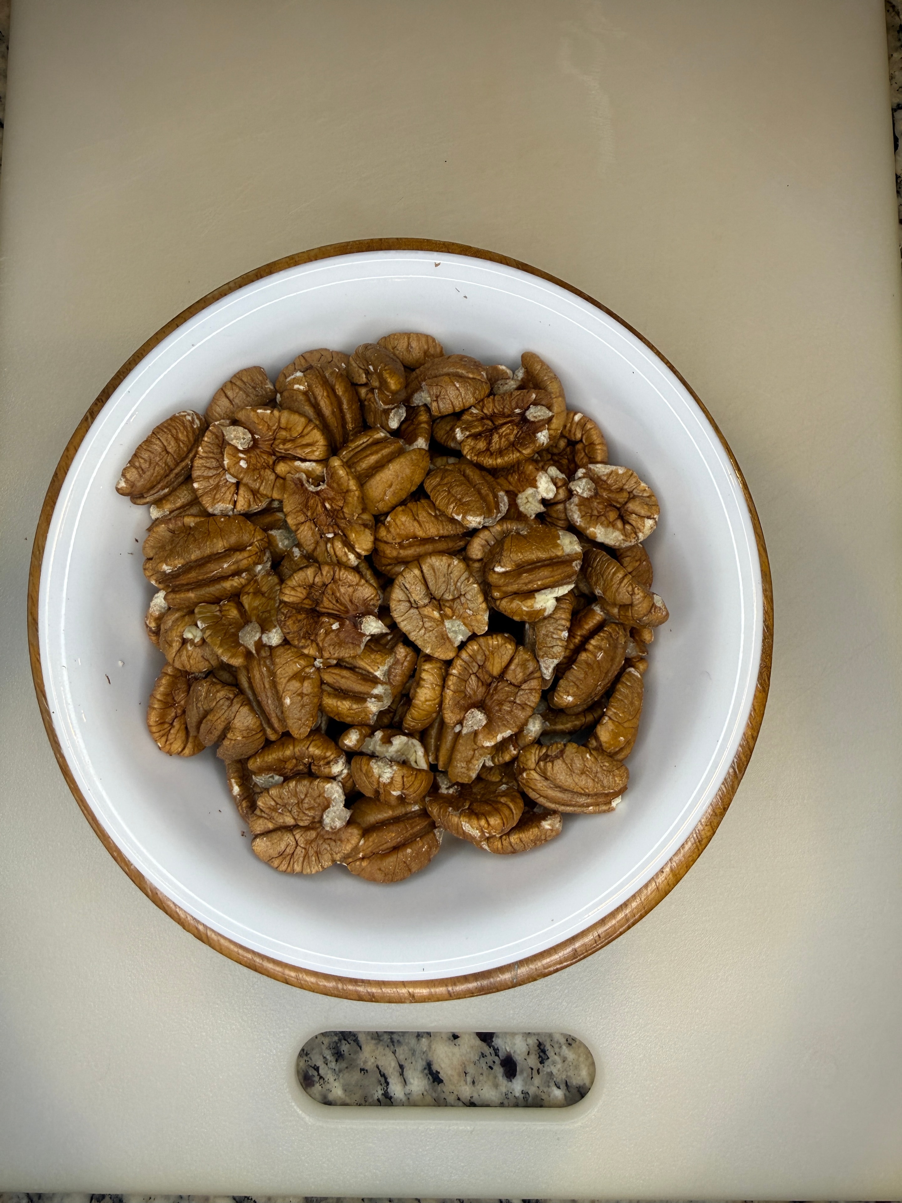 Cracked pecan halves in a rustic wooden bowl